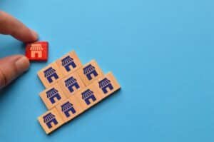 Man hand picked wooden block with store icons. Business empire and franchising concept